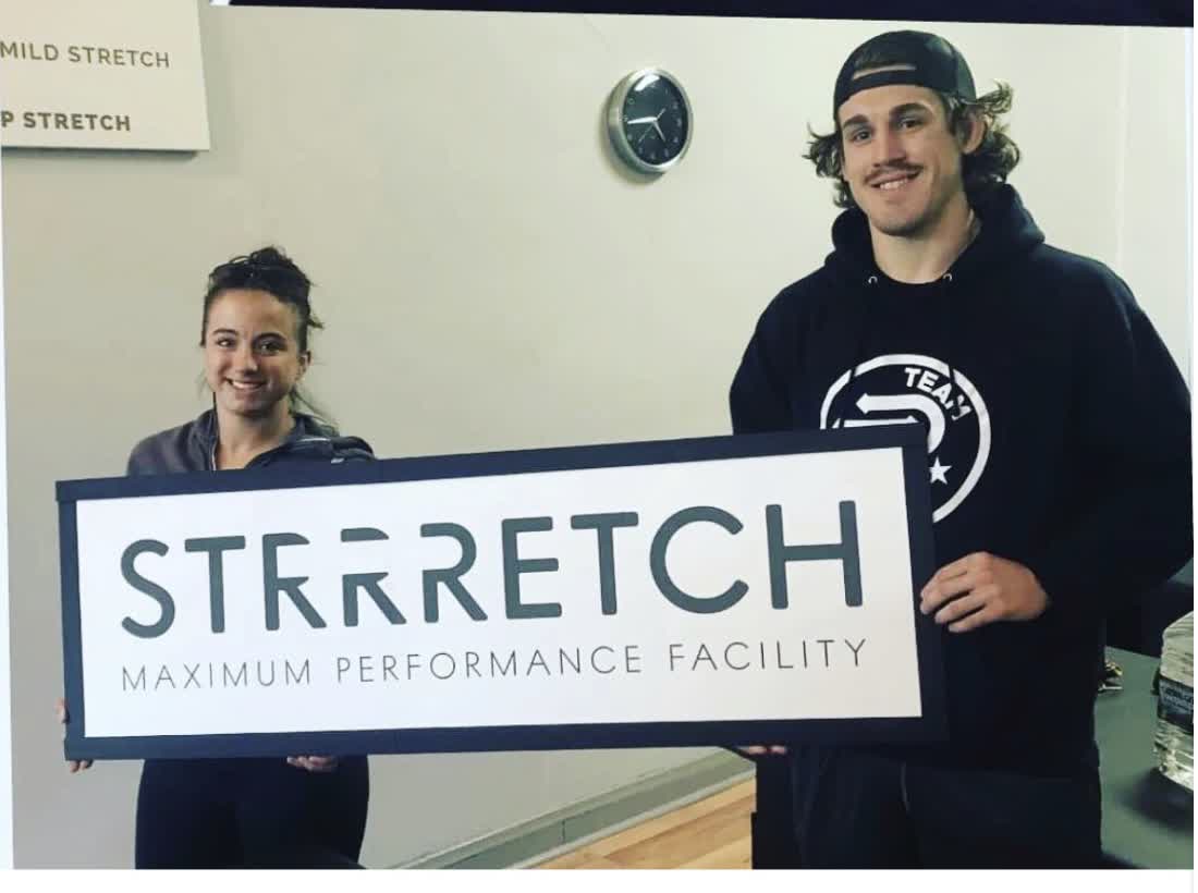 Maycee Barber and Brendan Allen holding a Strrretch sign at the studio