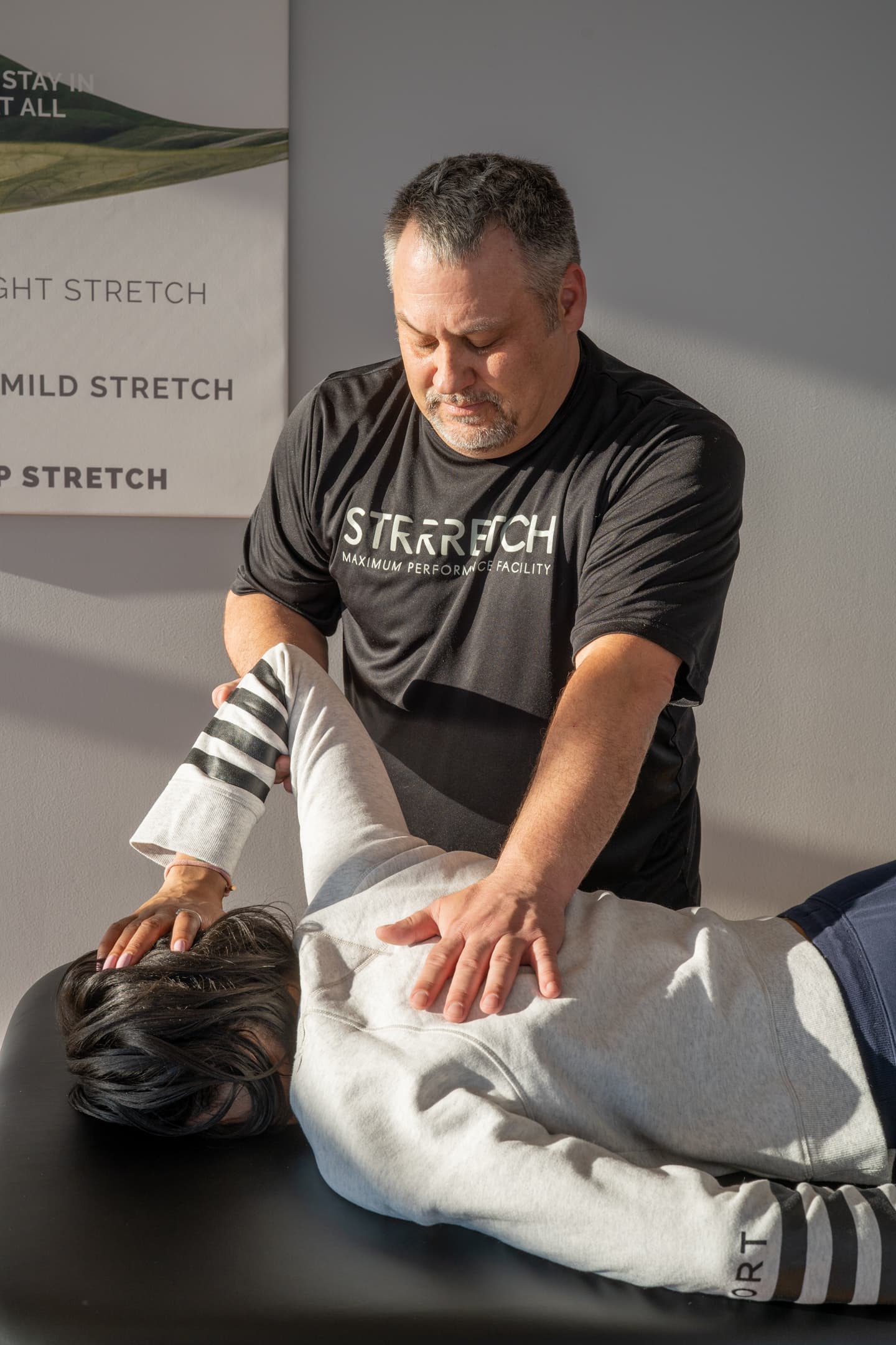 A Strrretch practitioner working through a client's shoulder and upper back during a 1-on-1 assisted stretch in Frisco, Texas