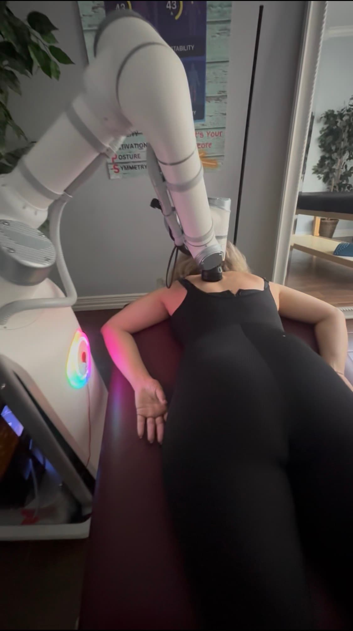 A client relaxing on a treatment table while the AI Robot Massage arm works across her shoulders at Strrretch Frisco